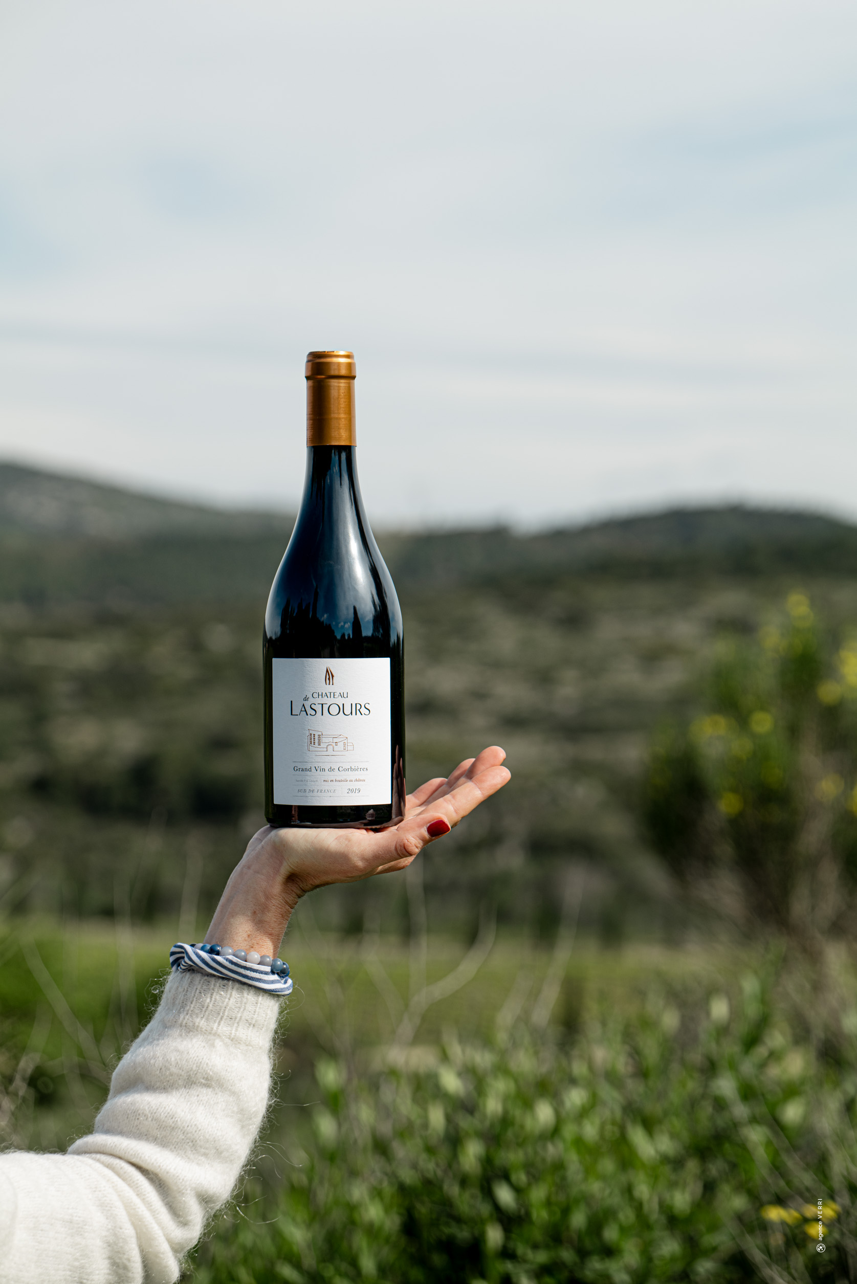 Bouteille de grand vin Château de Lastours présentée devant les vignes, photographie Agence Verri.