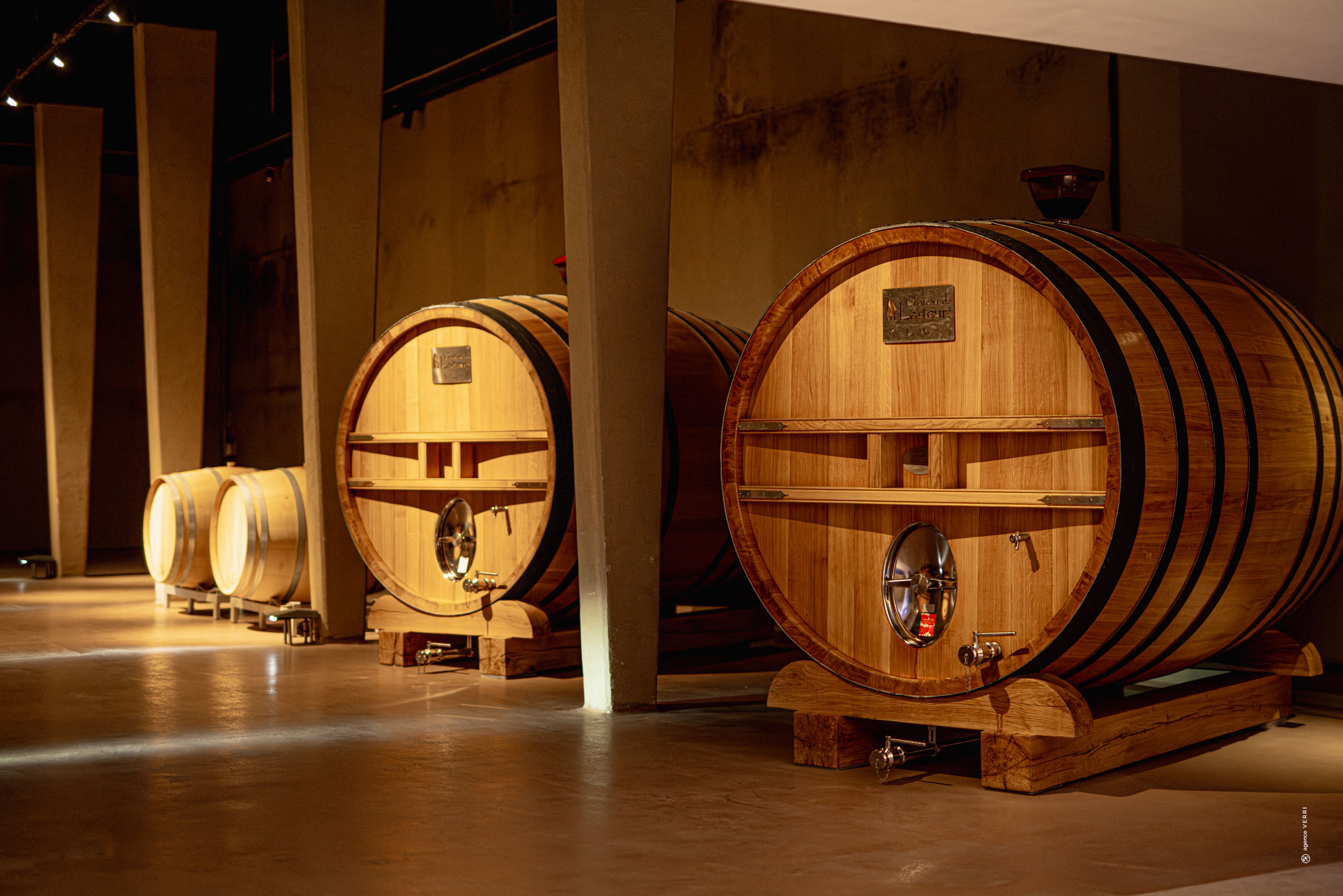 Grands foudres en bois dans le chai du Château de Lastours, photographie Agence Verri.